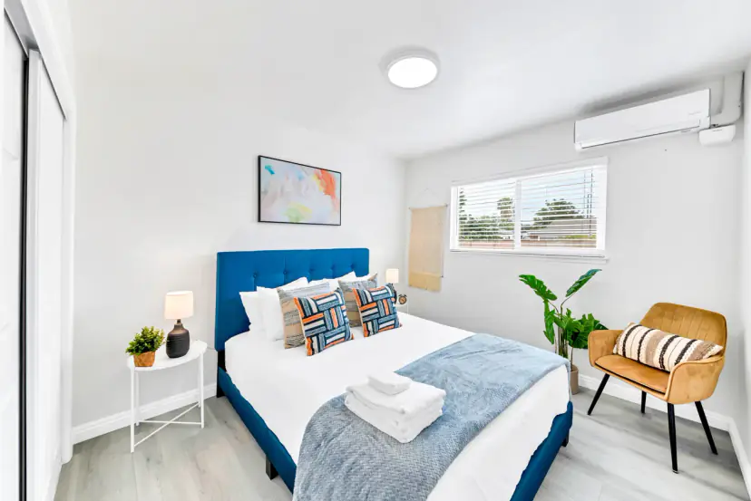 Bedroom with a blue tufted bed and a mustard armchair
