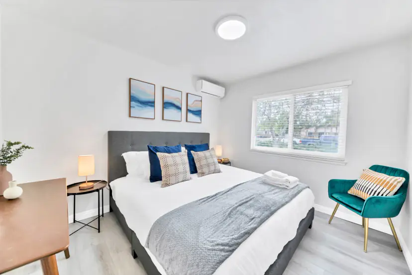 Bedroom with a grey bed, a teal chair and a blue triptych