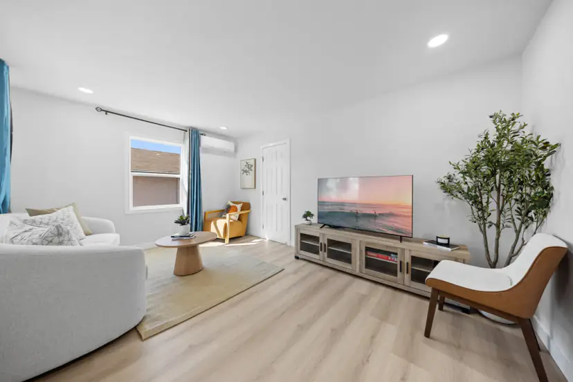 Living room with a curved sofa, TV and armchairs
