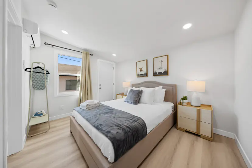 Queen bedroom with an upholstered bed and a clothes rack