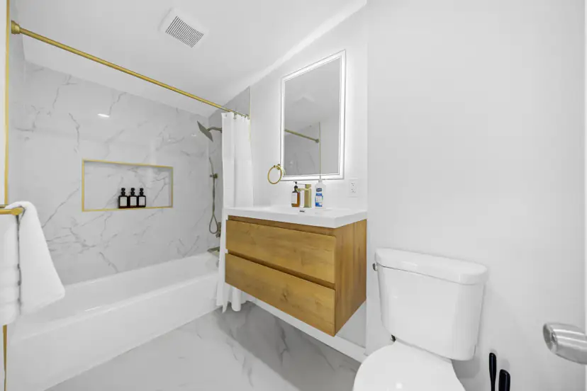 Bathroom with a tub, gold fixtures and a wood vanity