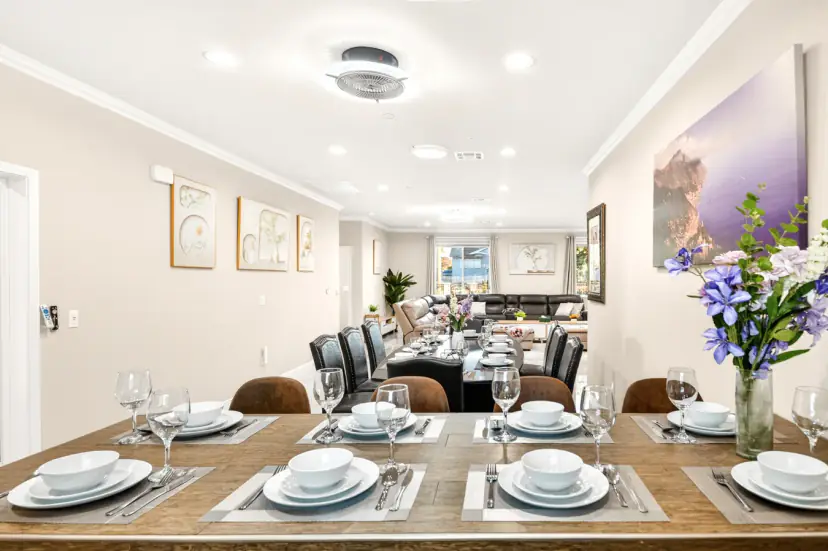 Long wood dining table set for a group, looking toward the living room
