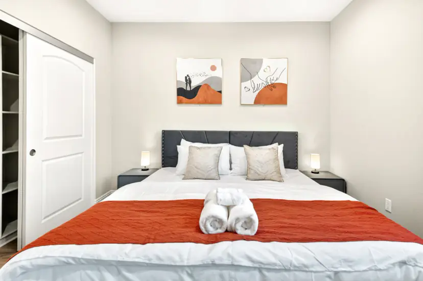 Bed with a grey headboard and orange throw