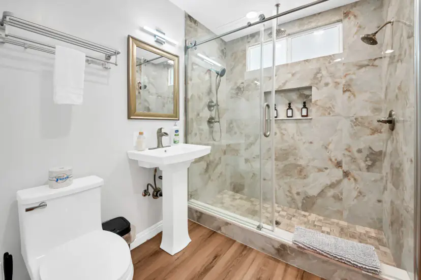 Bathroom with a marble-look glass shower and a pedestal sink