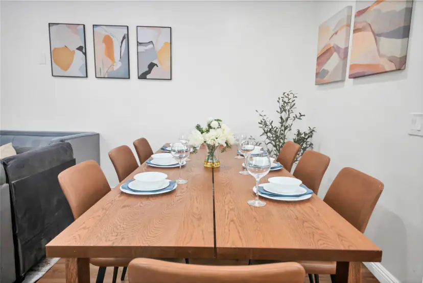 Dining table with tan leather chairs and abstract art