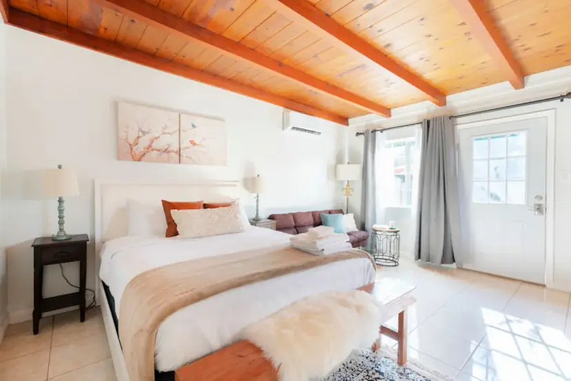 Studio with a queen bed under a wood plank ceiling and French doors