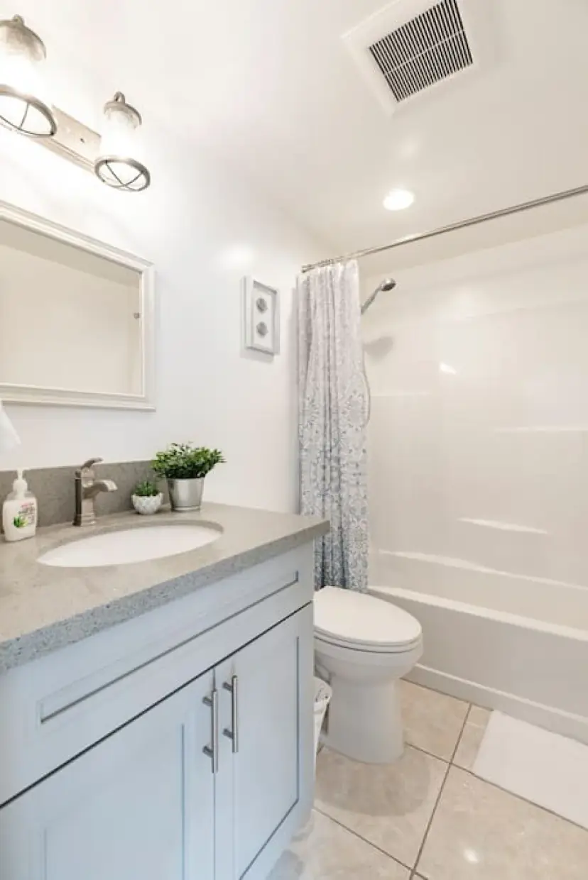 Bathroom with a grey vanity and a tub-shower
