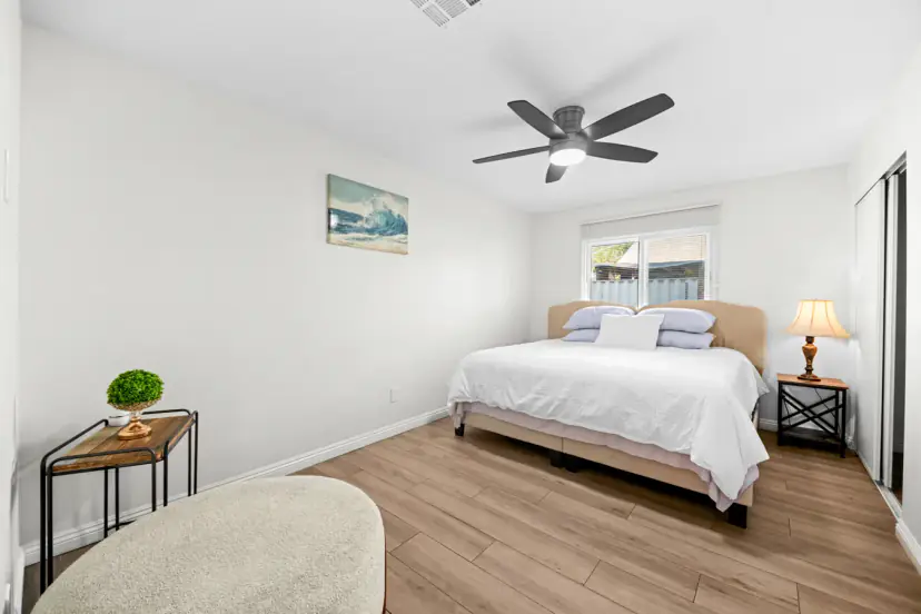 King bed with wave art and a ceiling fan