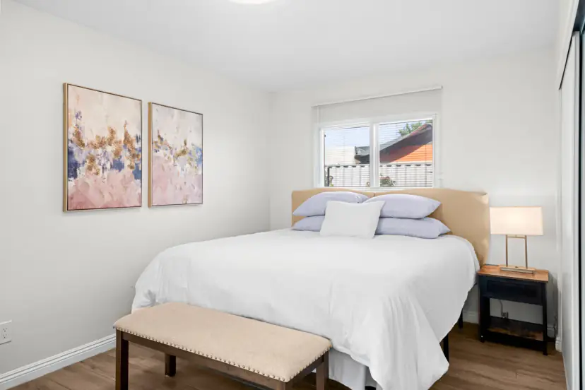 Queen bed with a bench and pink abstract art