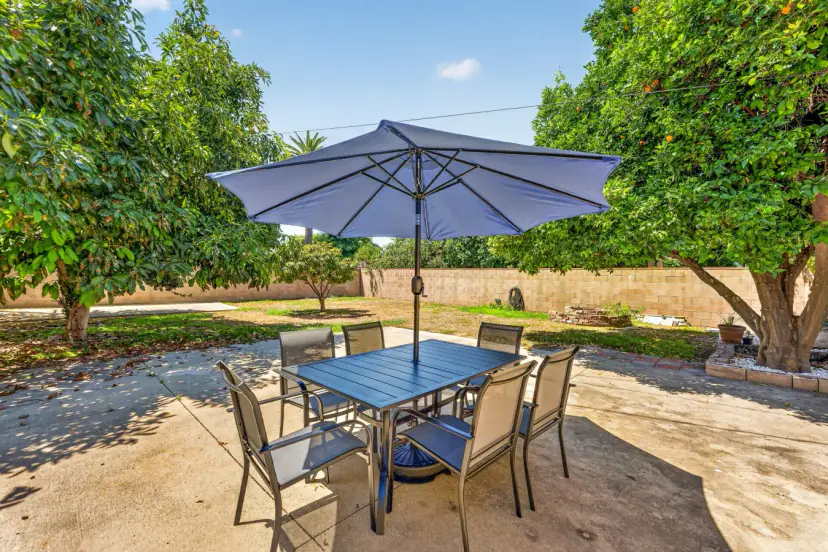 Backyard dining table under a blue umbrella