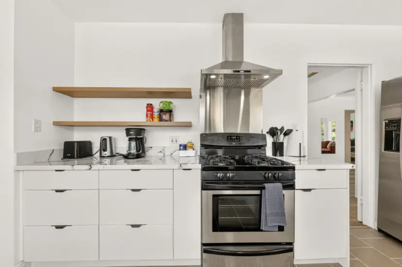 White kitchen with a gas range and floating shelves