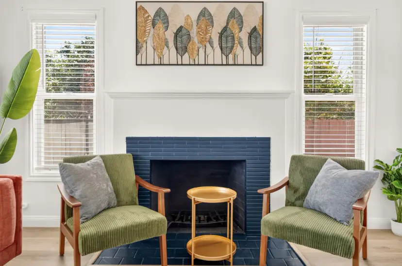 Navy-tiled fireplace between green velvet armchairs
