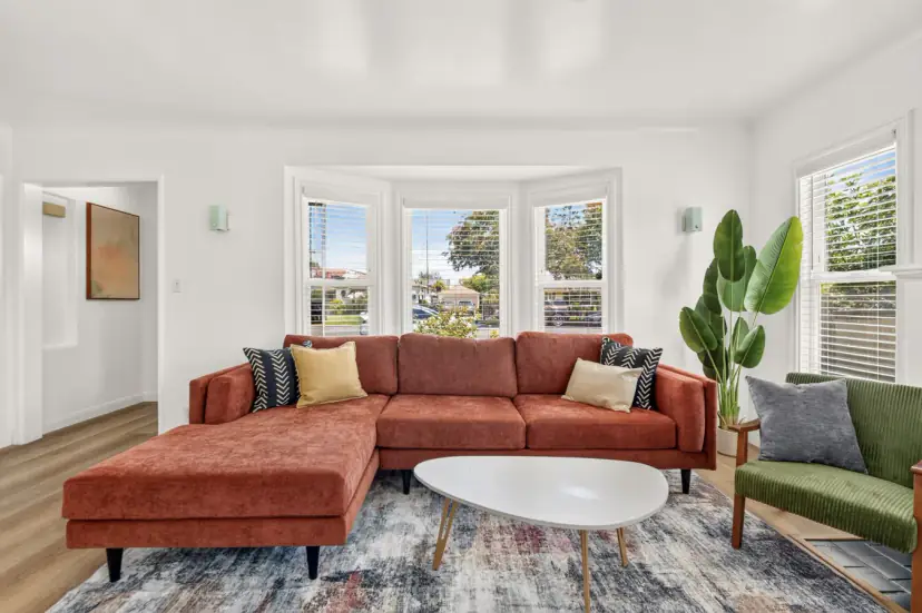 Living room with a rust sectional and a bay window