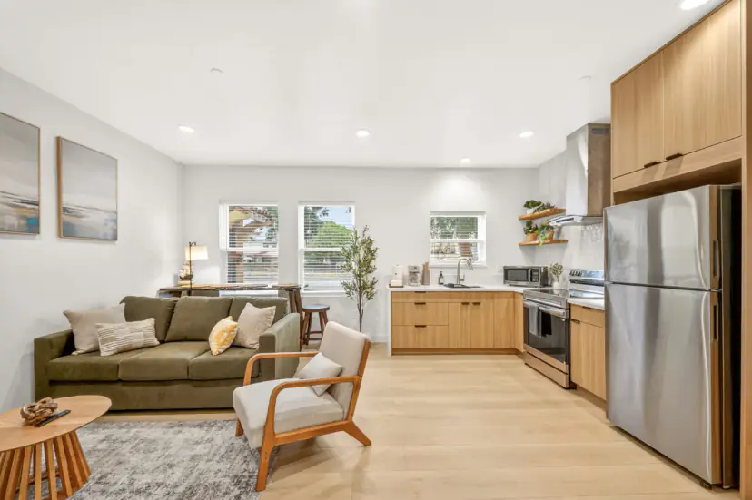 Open living room and kitchen with a green sofa and light wood cabinets