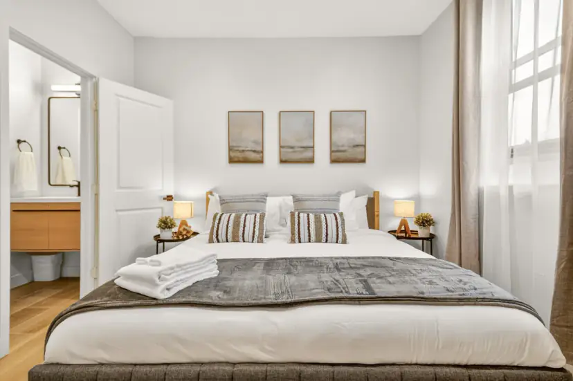 Bedroom with a large bed, striped pillows and a bathroom door