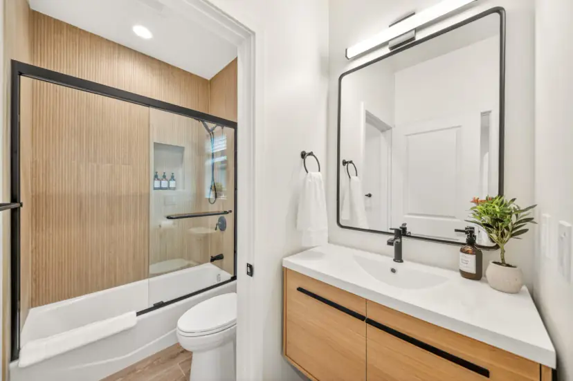 Bathroom with a tub, wood-look tile and a black-framed mirror