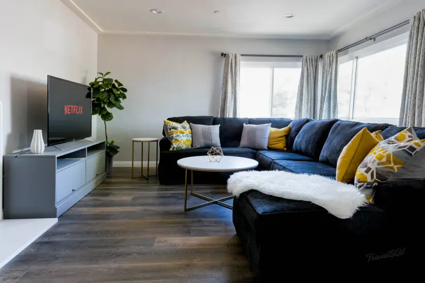 Living room with a navy sectional, mustard pillows and a TV