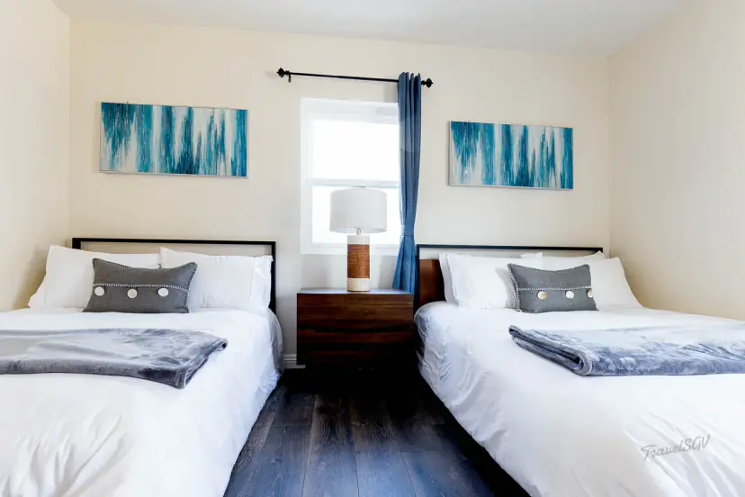 Two beds with grey throws and teal art