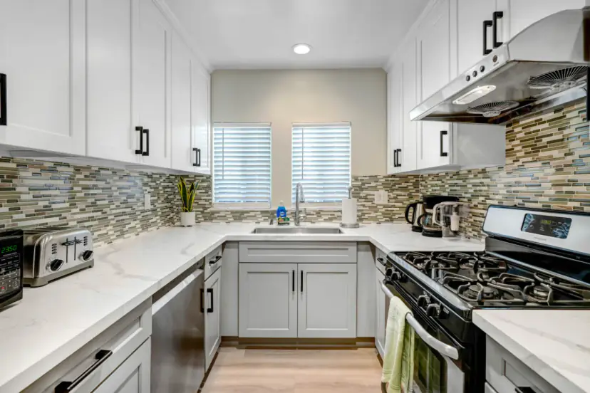 White shaker kitchen with a mosaic backsplash and a gas range