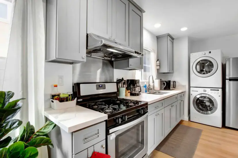 Grey shaker kitchen with a gas range and a stacked washer and dryer