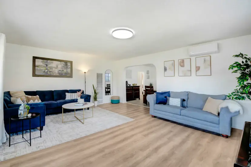 Living room with two blue sofas and an arch to the dining room