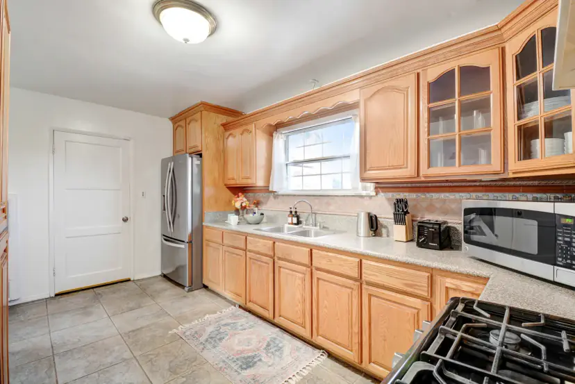 Honey-oak kitchen with a gas range, a microwave and a stainless fridge