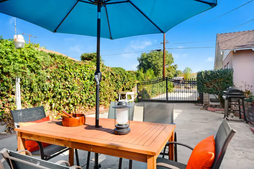 Outdoor table under a blue umbrella with orange cushions
