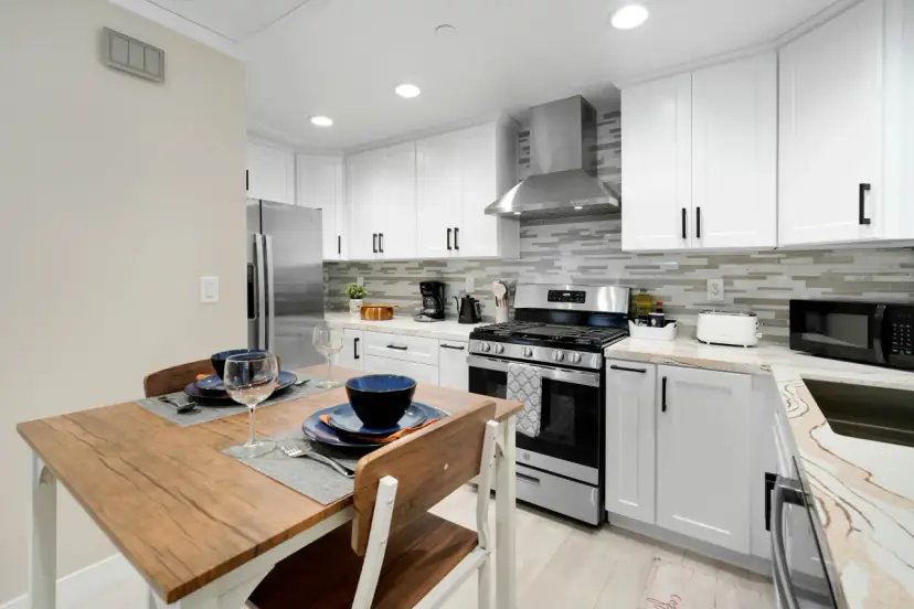 Small dining table beside a white kitchen with a gas range