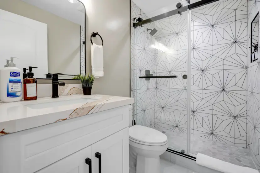 Bathroom with a patterned-tile glass shower and a white vanity