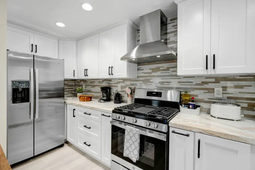 White kitchen with a stainless fridge and a gas range