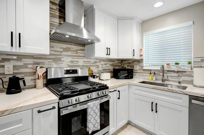 Kitchen with a mosaic tile backsplash and a range hood
