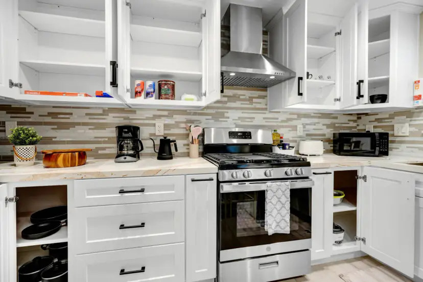 Kitchen with white shaker cabinets, a gas range and open shelves