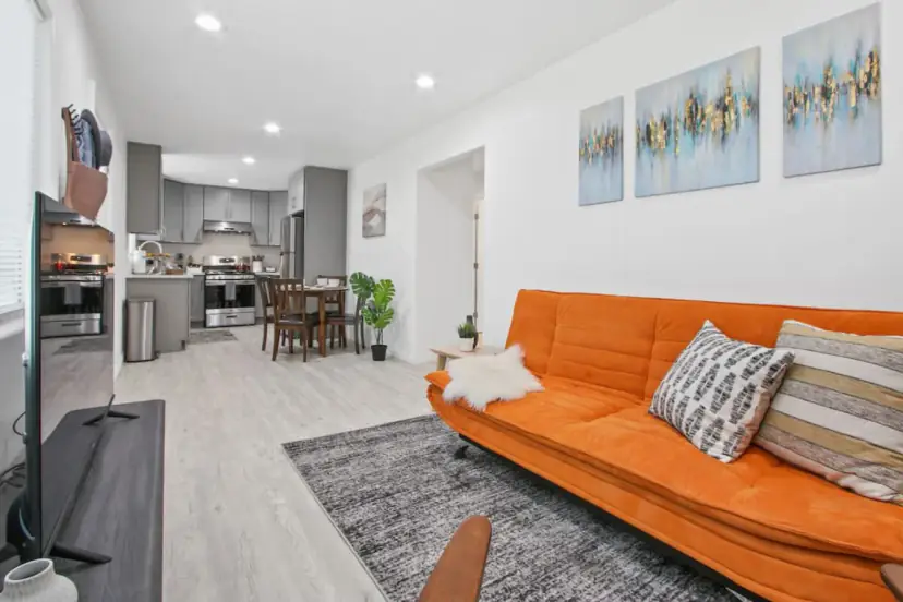Living room with an orange futon sofa and a wall TV