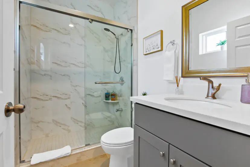 Bathroom with a marble-look shower and a grey vanity