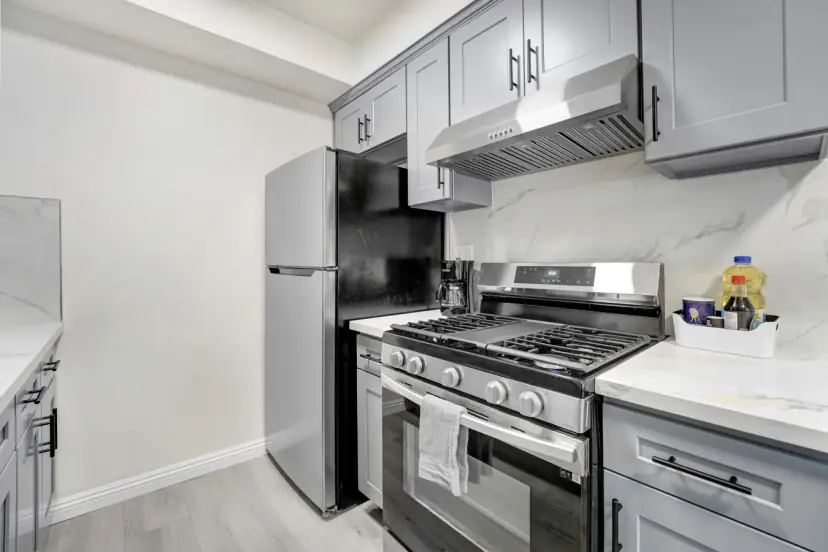 Grey shaker kitchen with a gas range and a stainless fridge