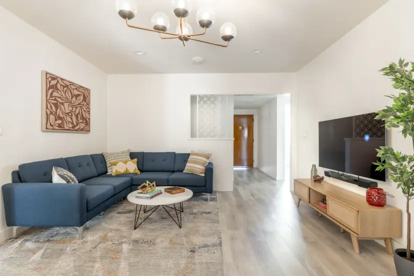 Living room with a navy sectional, a round coffee table and a mid-century chandelier