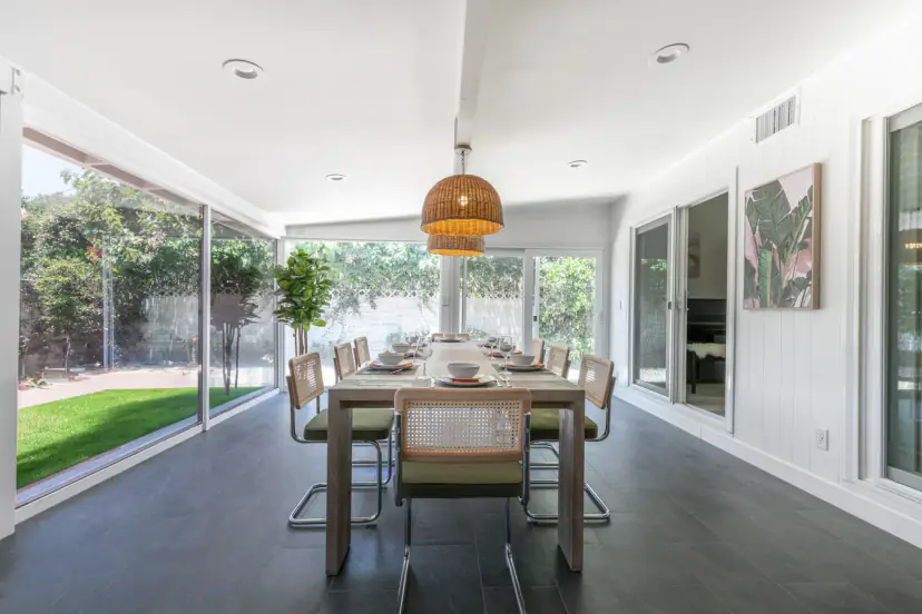 Glass-walled dining room with cane chairs looking onto the lawn