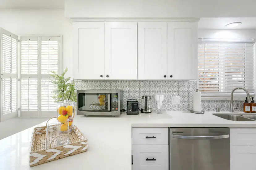 White kitchen with patterned tile, a microwave and a dishwasher
