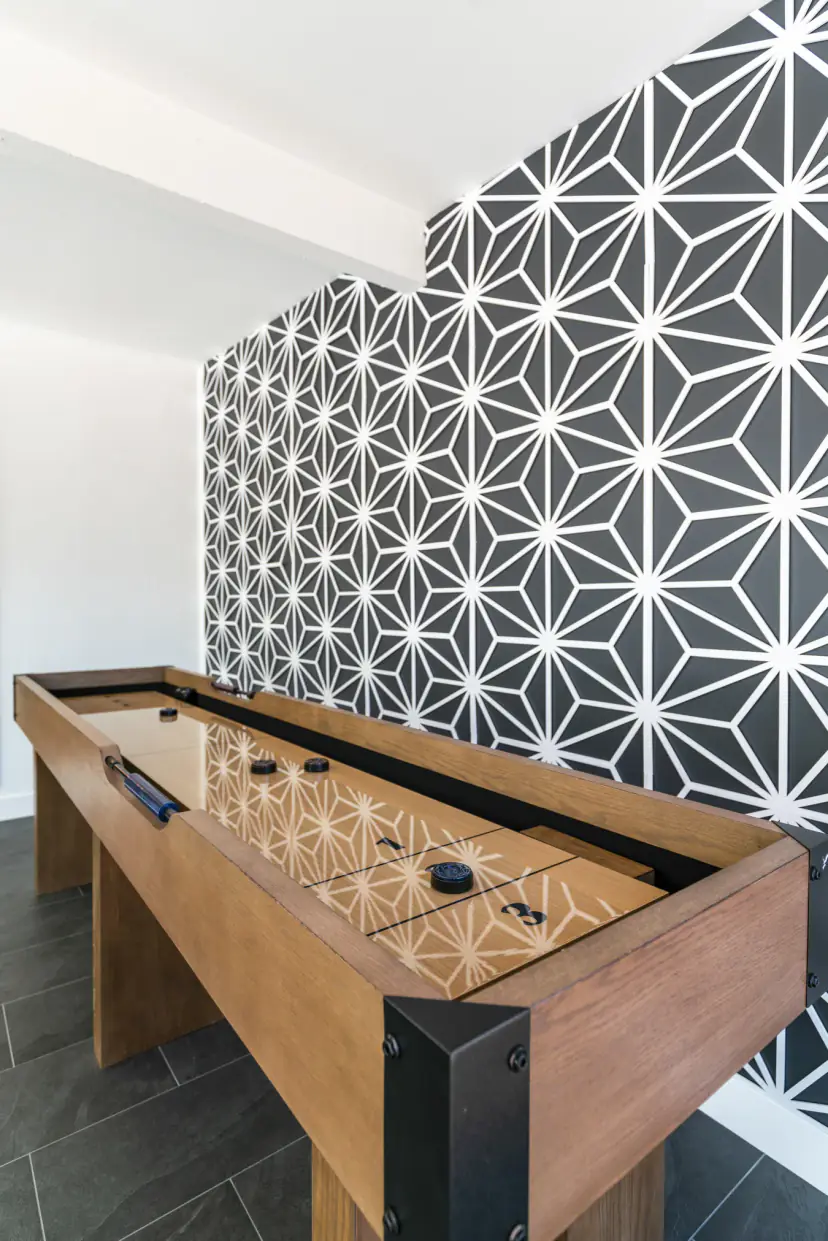 Wooden shuffleboard table against black and white star wallpaper