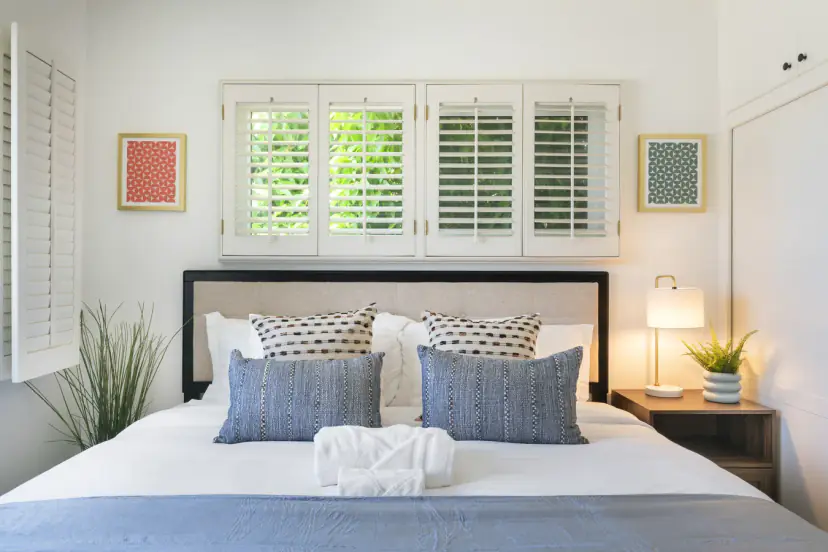 Bedroom with a king bed, a lamp-lit nightstand and plantation shutters