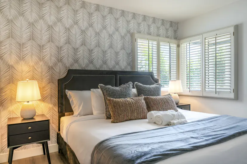 Main bedroom with a dark headboard against leaf-pattern wallpaper