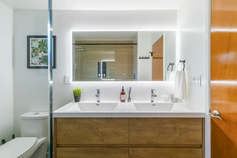 Bathroom with a double vanity, a backlit mirror and a wood cabinet