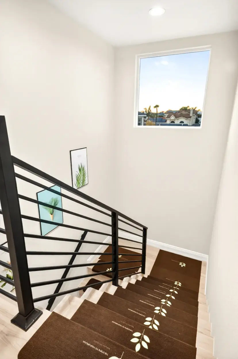 Staircase with a black railing and a large window