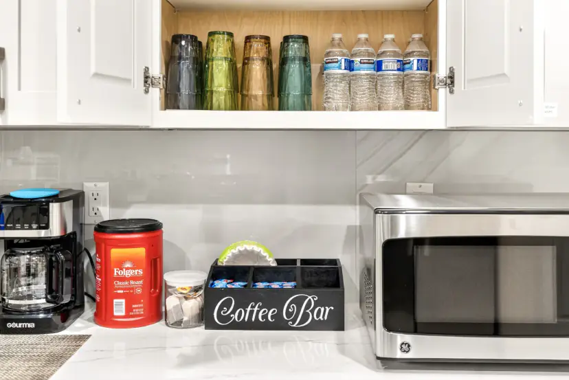 Coffee bar with glasses, bottled water and a microwave