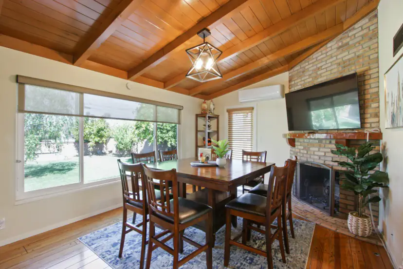 Dining table by a brick fireplace under a wood-beam ceiling