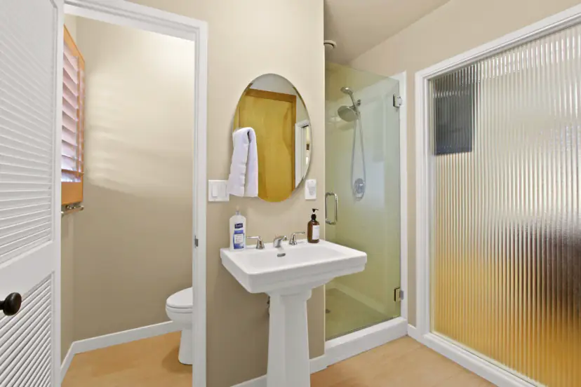 Bathroom with a pedestal sink and a glass shower