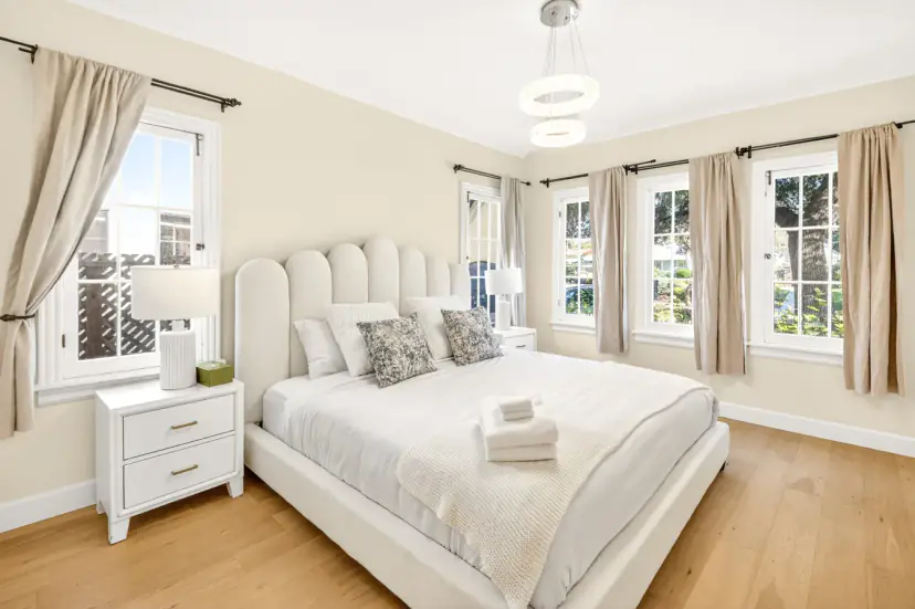 Bright bedroom with a scalloped headboard and four windows