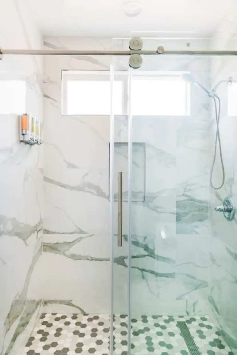 Marble-look walk-in shower with a glass door