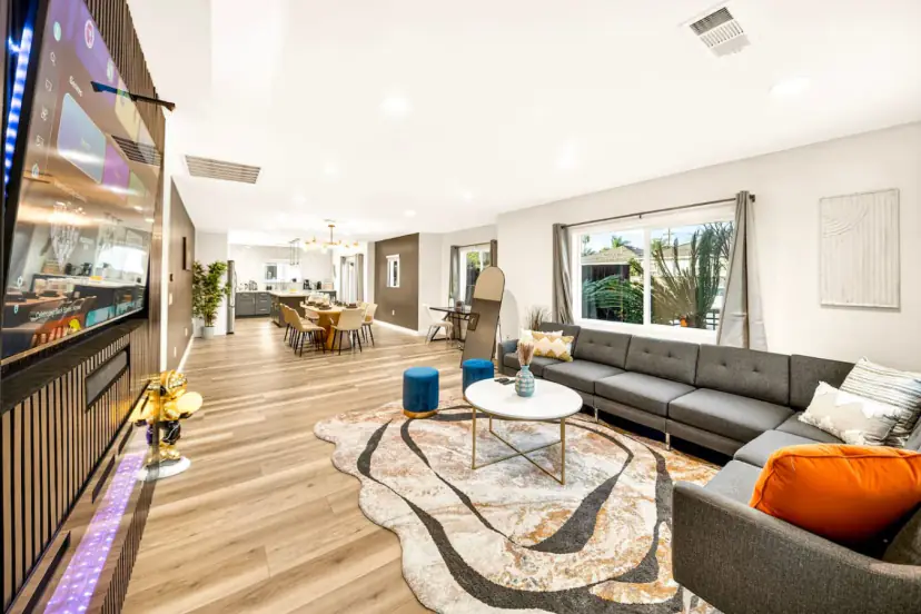 Open living room with a large grey sectional, rug and wood floors, with the dining area beyond