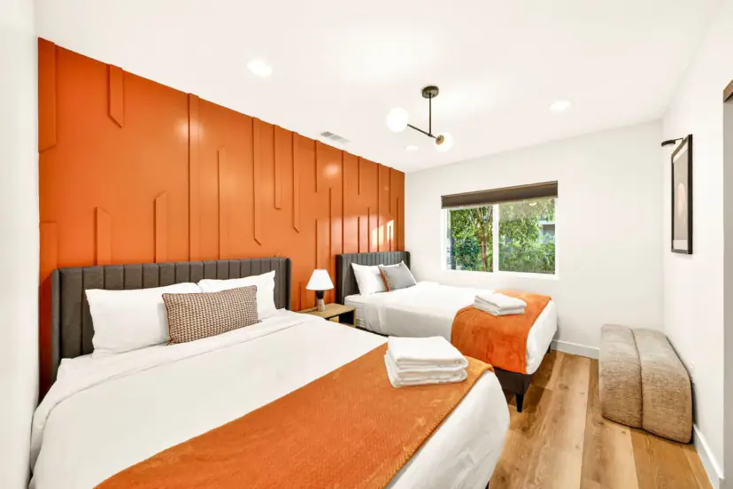 Bedroom with two beds under an orange accent wall